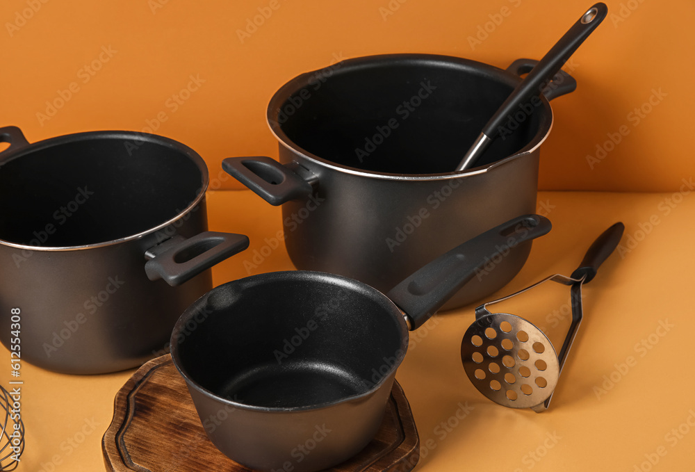 Set of kitchen pots and kitchen utensils on color background