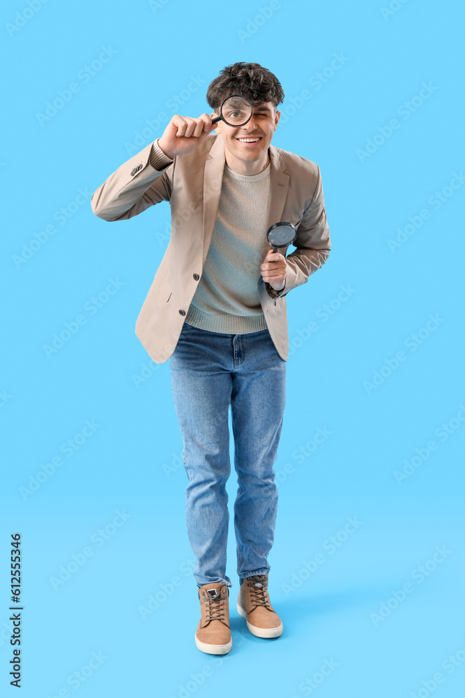 Young man with magnifiers on blue background