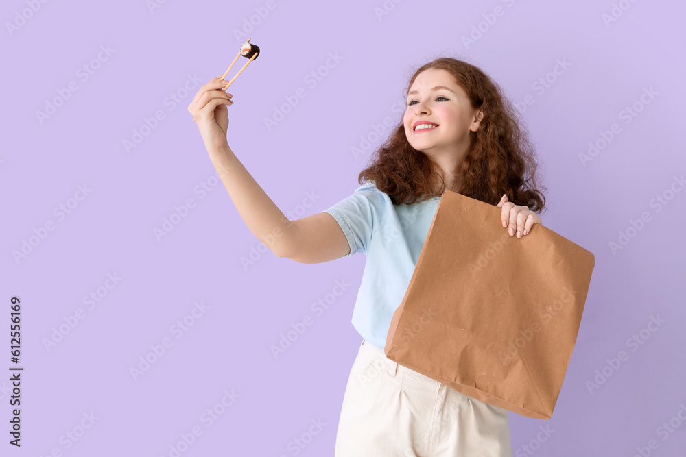 Young woman with sushi roll and paper bag on lilac background