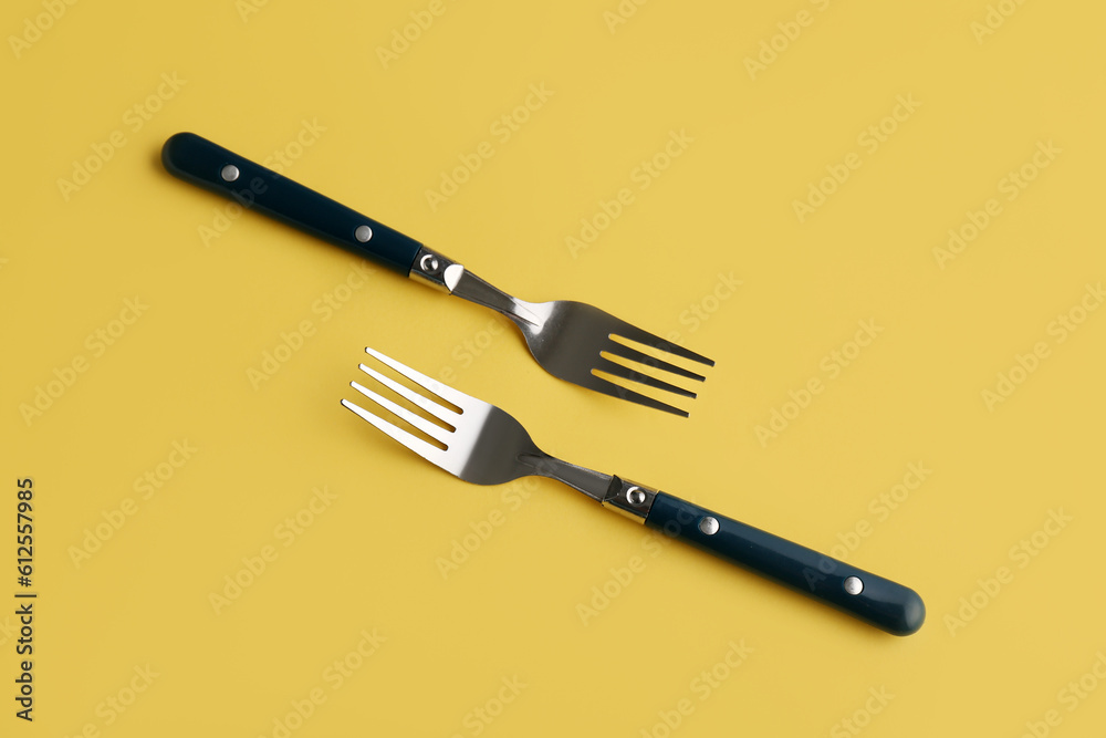 Stylish forks on yellow background