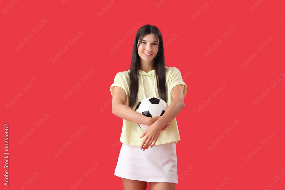 Young woman with soccer ball on red background