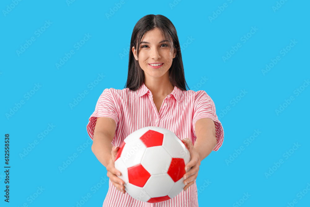 Young woman with soccer ball on blue background