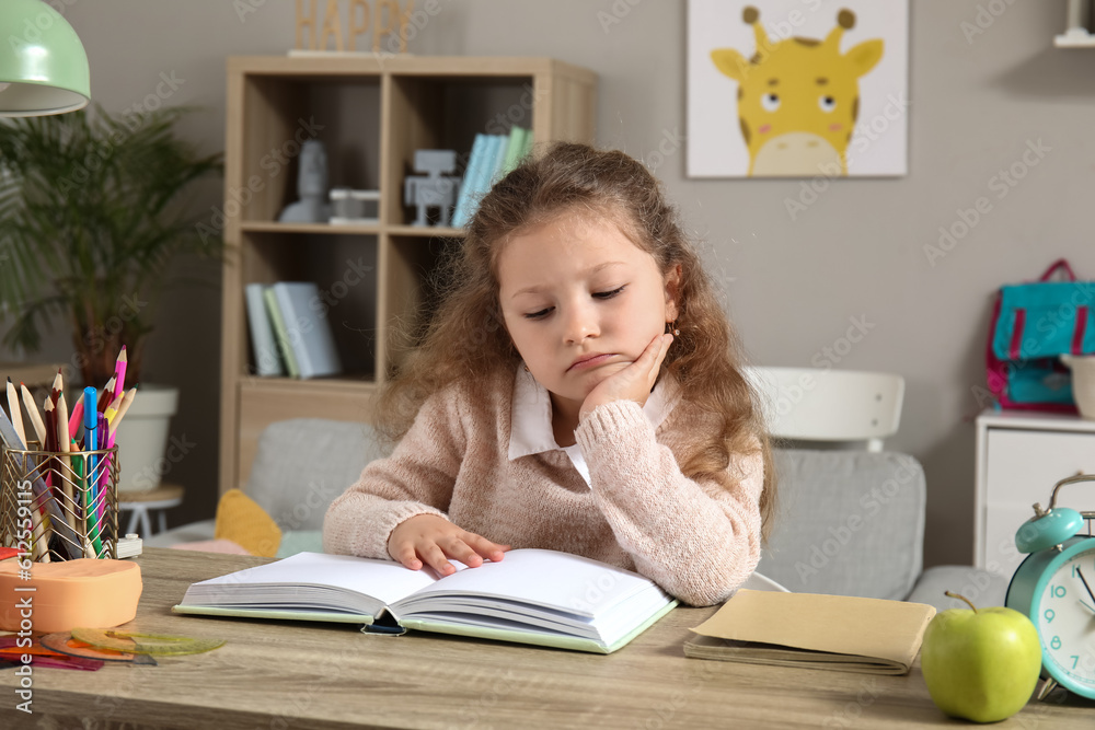 Sad little girl reading book at home