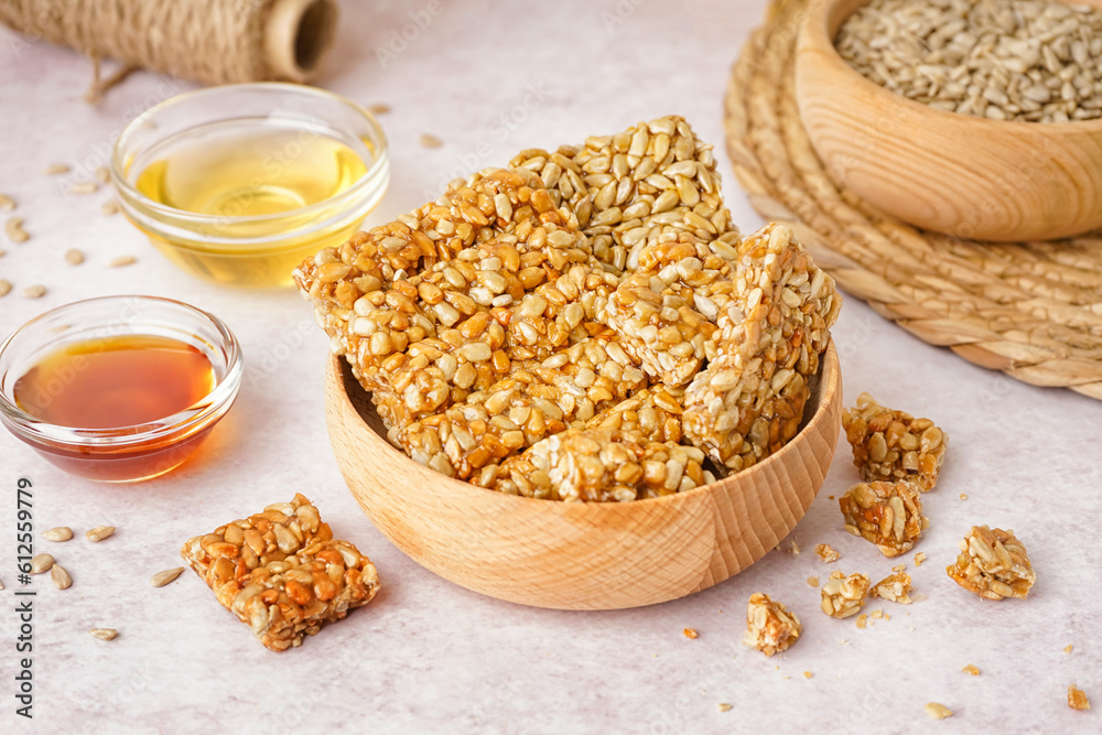 Bowls with tasty kozinaki, honey and sunflower seeds on white background