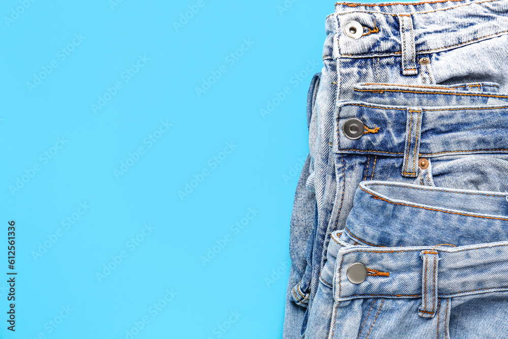 Different stylish jeans on blue background