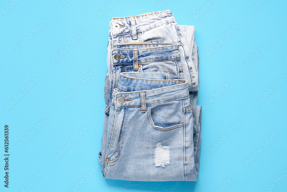 Different stylish jeans on blue background