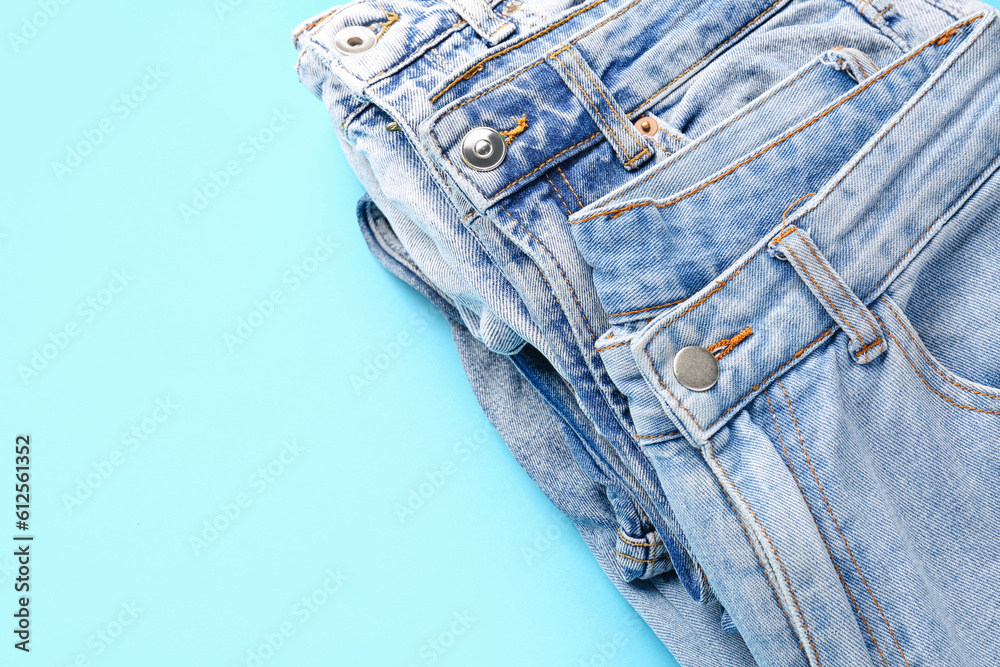 Different stylish jeans on blue background