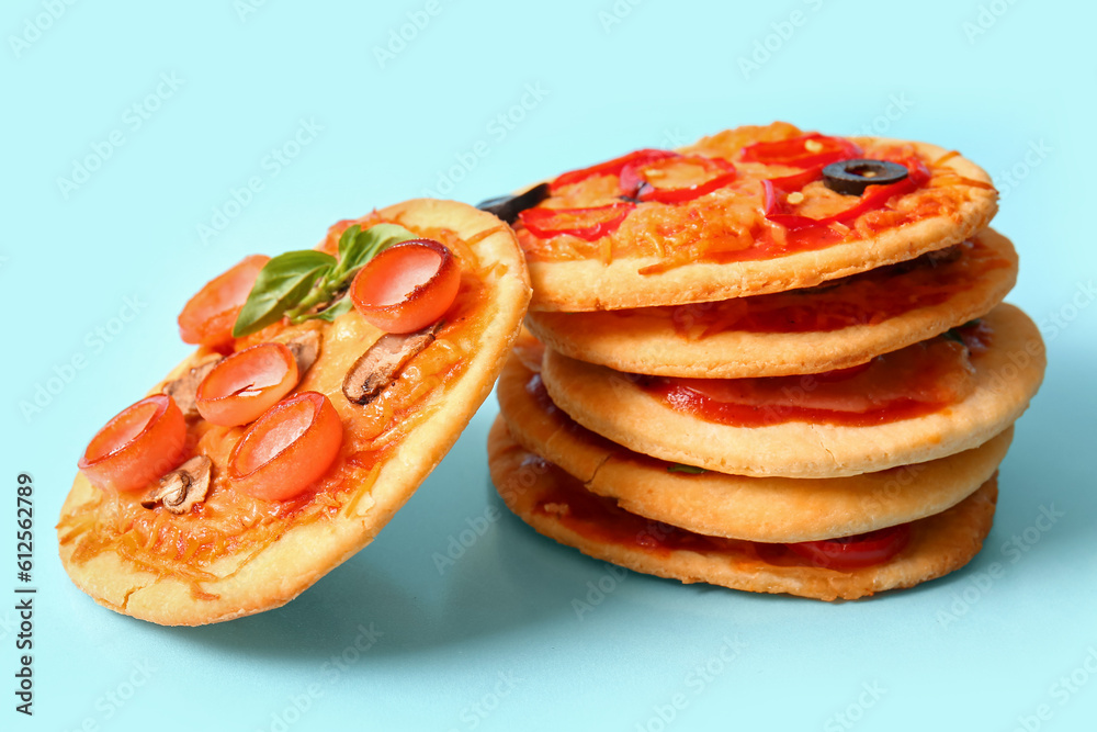 Different tasty mini pizzas on blue background