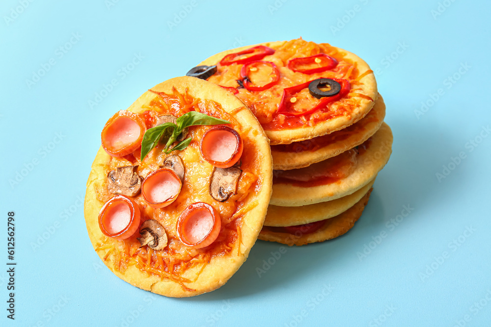 Different tasty mini pizzas on blue background