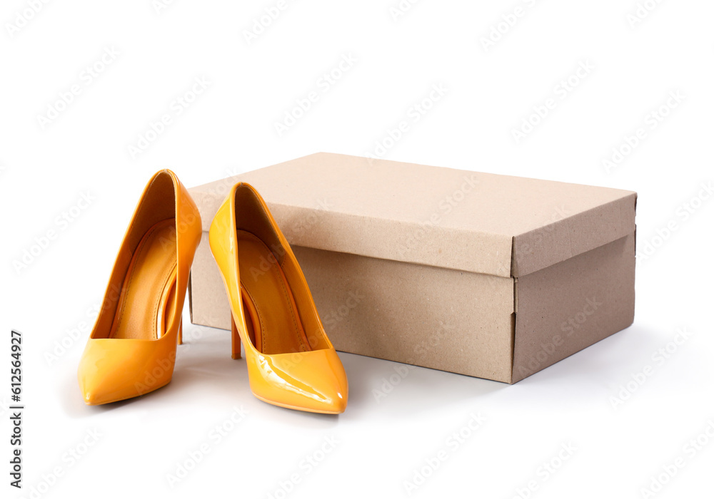 Cardboard box with stylish high-heeled shoes on white background