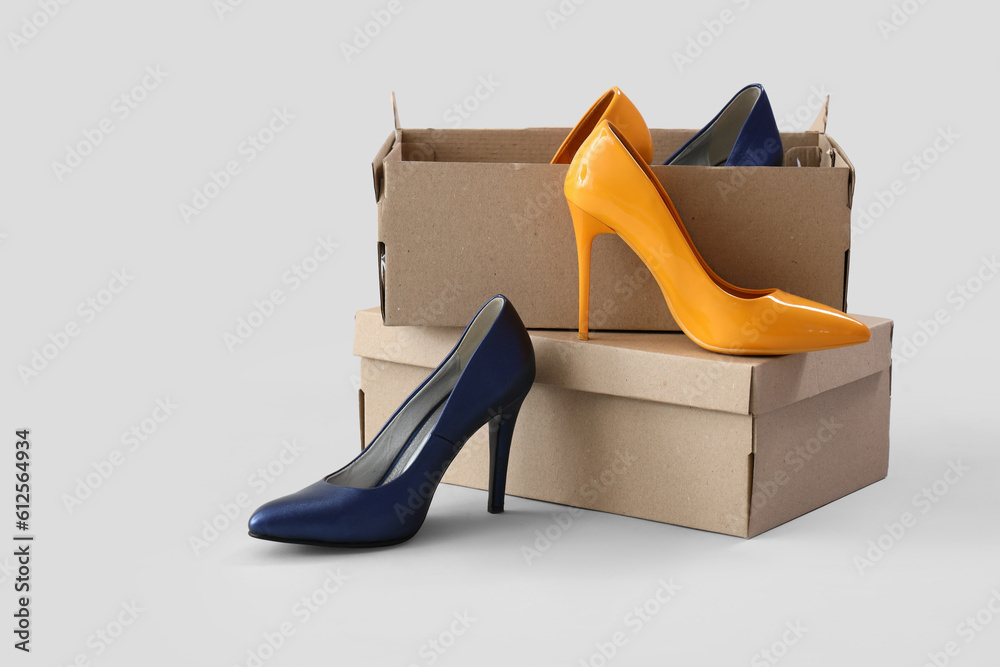 Cardboard boxes with stylish high-heeled shoes on white background