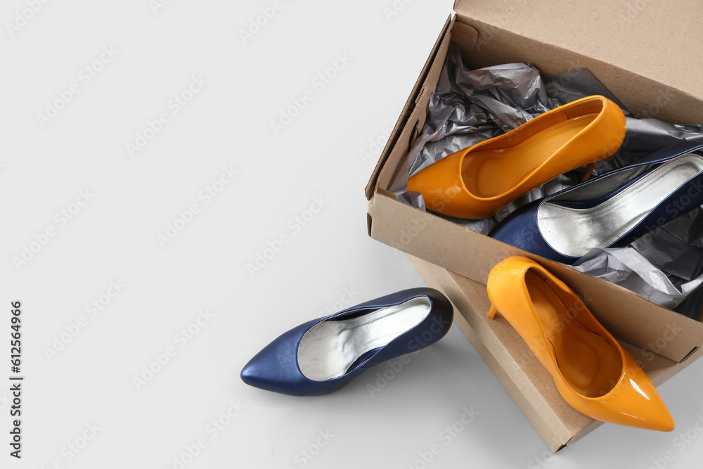 Cardboard boxes with stylish high-heeled shoes on white background