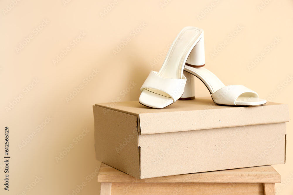 Cardboard boxes with stylish heeled shoes on beige background