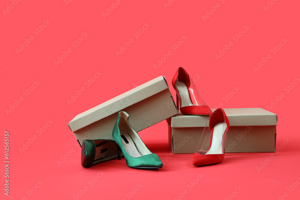 Cardboard boxes with different high-heeled shoes on red background