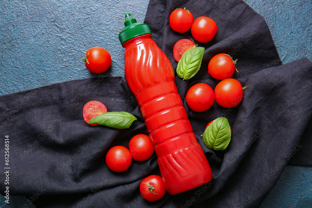 Bottle of ketchup and tomatoes on dark background