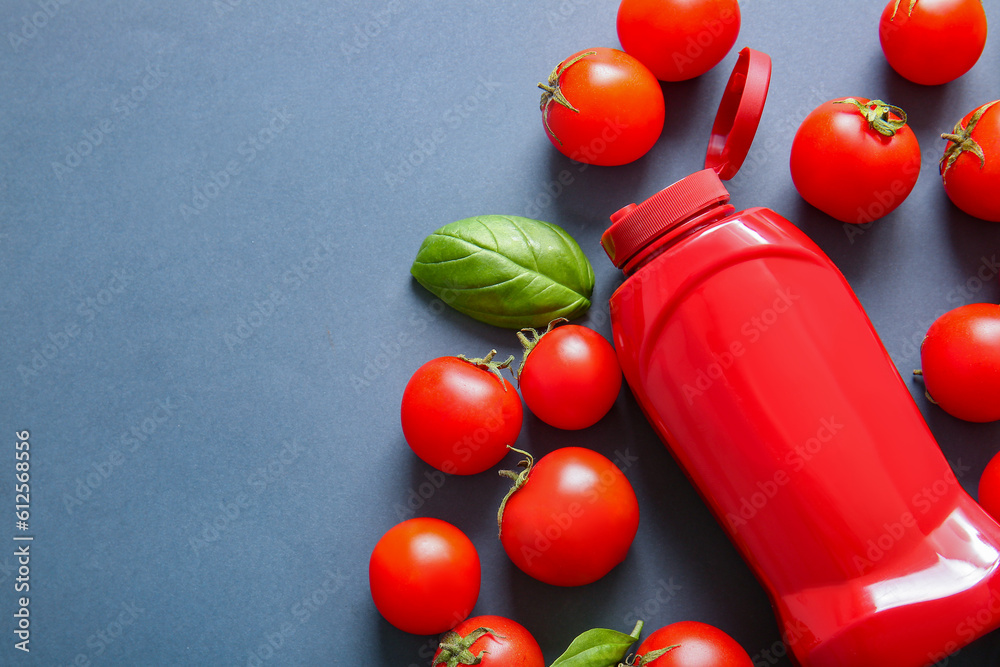 Bottle of ketchup and tomatoes on grey background