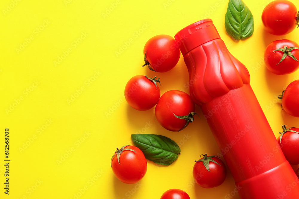 Bottle of ketchup and tomatoes on yellow background