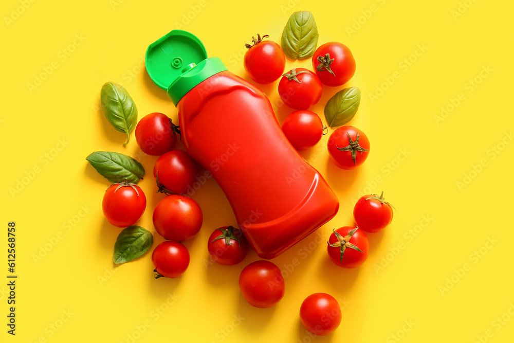 Bottle of ketchup and tomatoes on yellow background