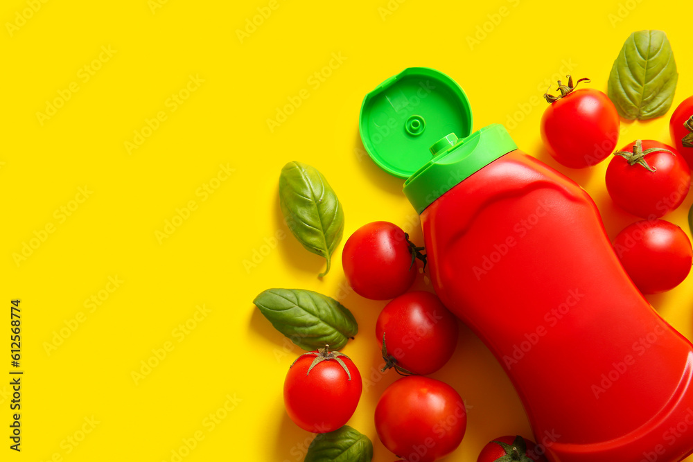 Bottle of ketchup and tomatoes on yellow background