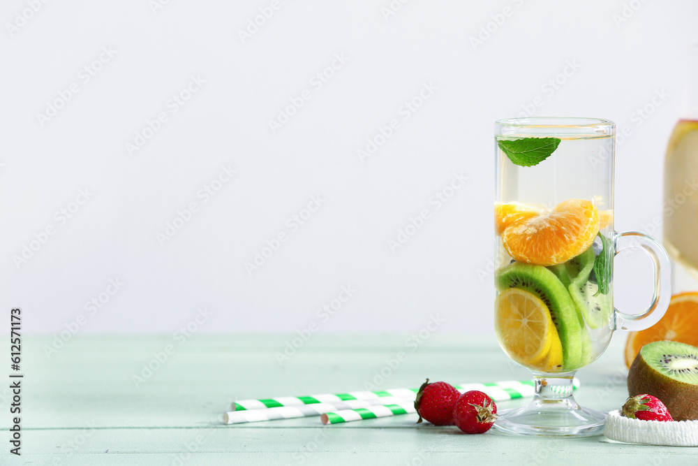 Glass of infused water with different sliced fruits on grey table