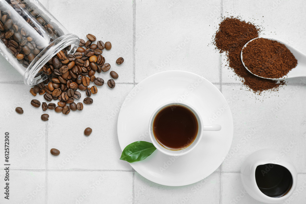 Cup of hot espresso, coffee beans and powder on white tile background