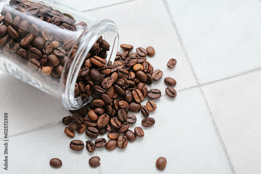 Jar with coffee beans on white tile background