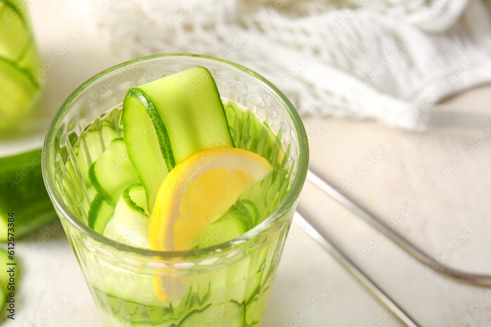 Glass of infused water with cucumber slices on white table