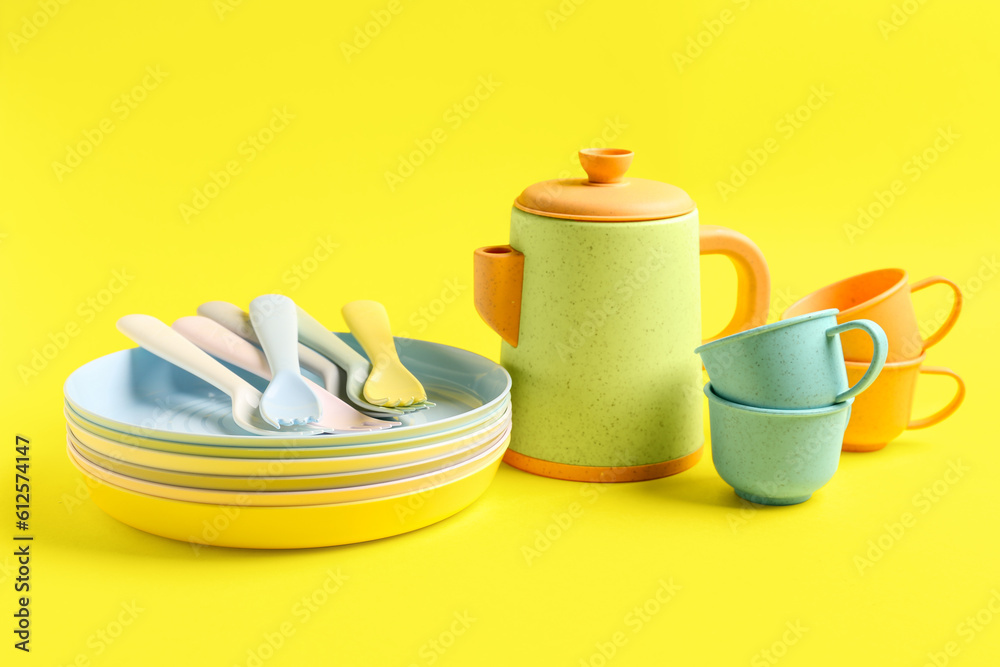 Different eating utensils for baby on yellow background