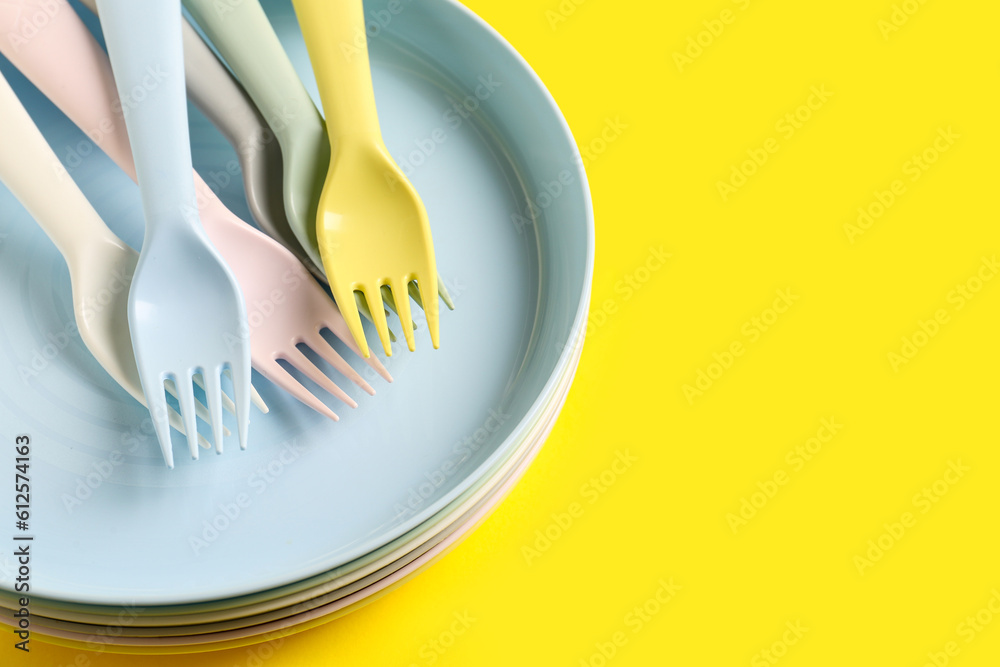 Many plates with forks for baby on yellow background