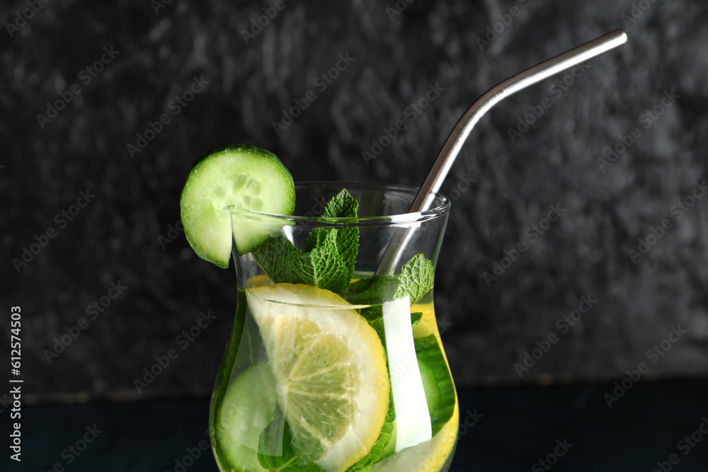 Glass of infused water with cucumber slices on black background