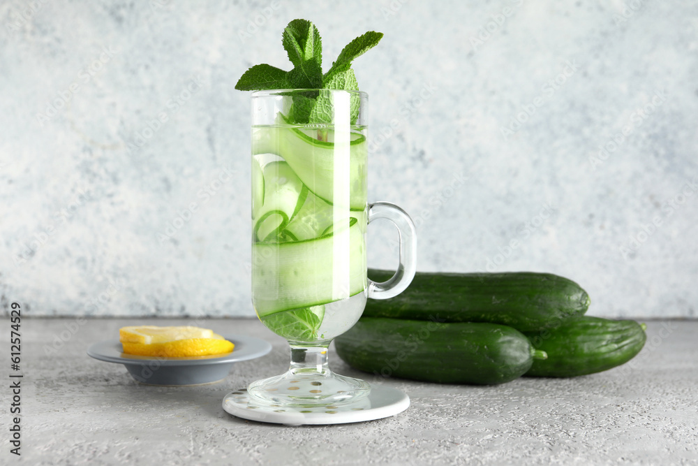 Glass of infused water with cucumber slices on grey table