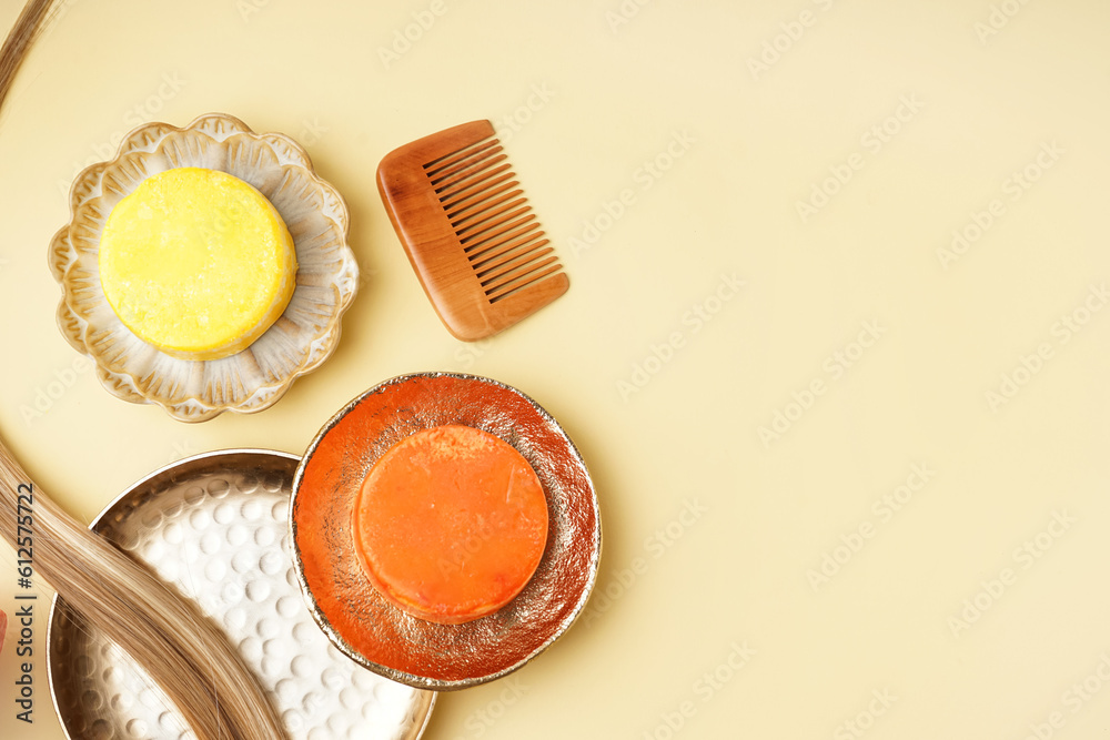 Plates with solid shampoo bars, comp and hair on yellow background