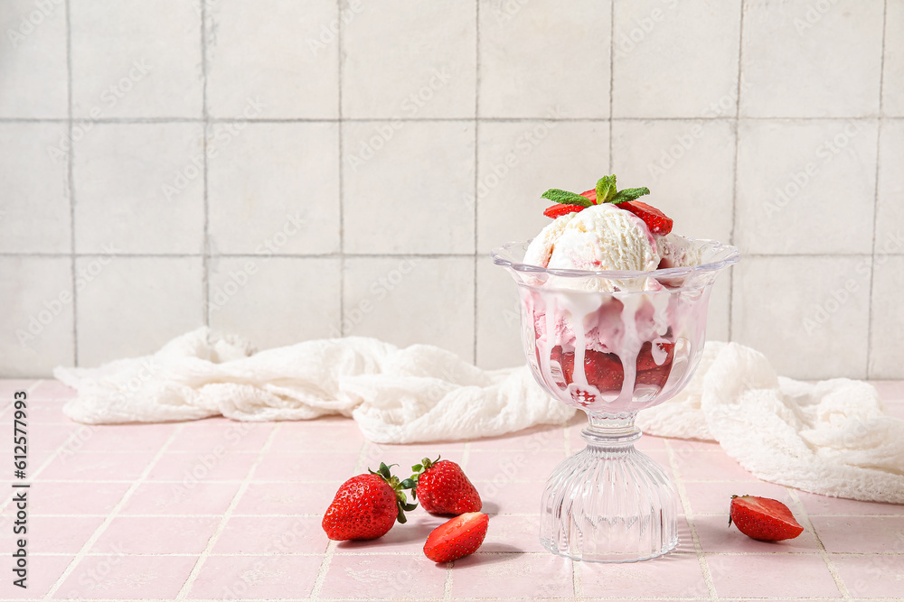 Bowl of vanilla ice cream with strawberries, mint and tablecloth on pink tile table near white wall