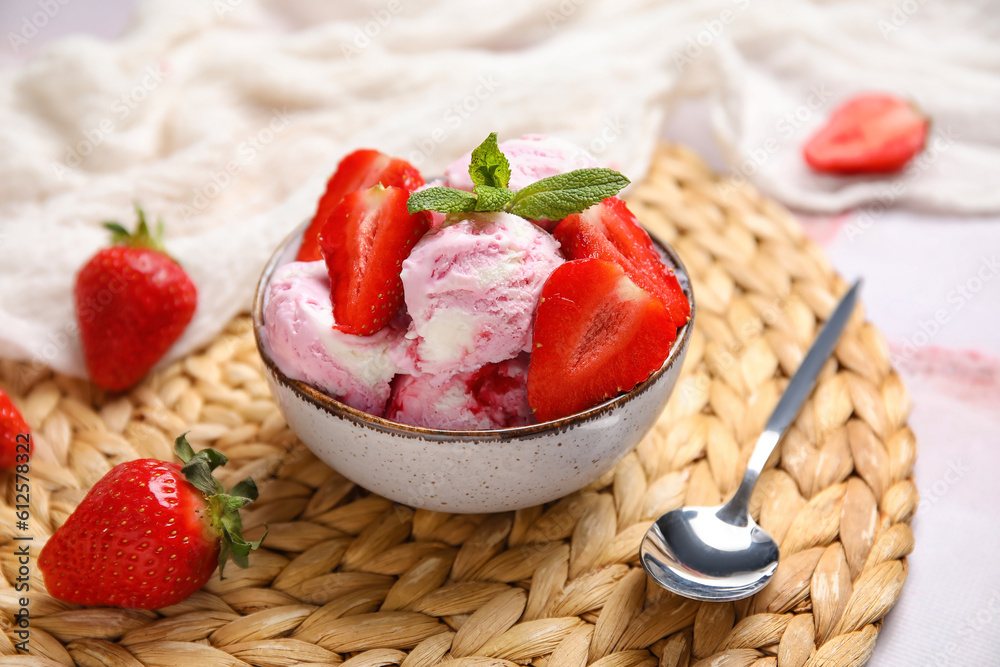 Bowl of strawberry ice cream with berries, mint and spoon on pink table