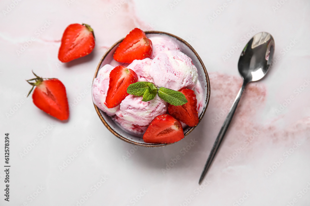 Bowl of strawberry ice cream with berries, mint and spoon on pink table