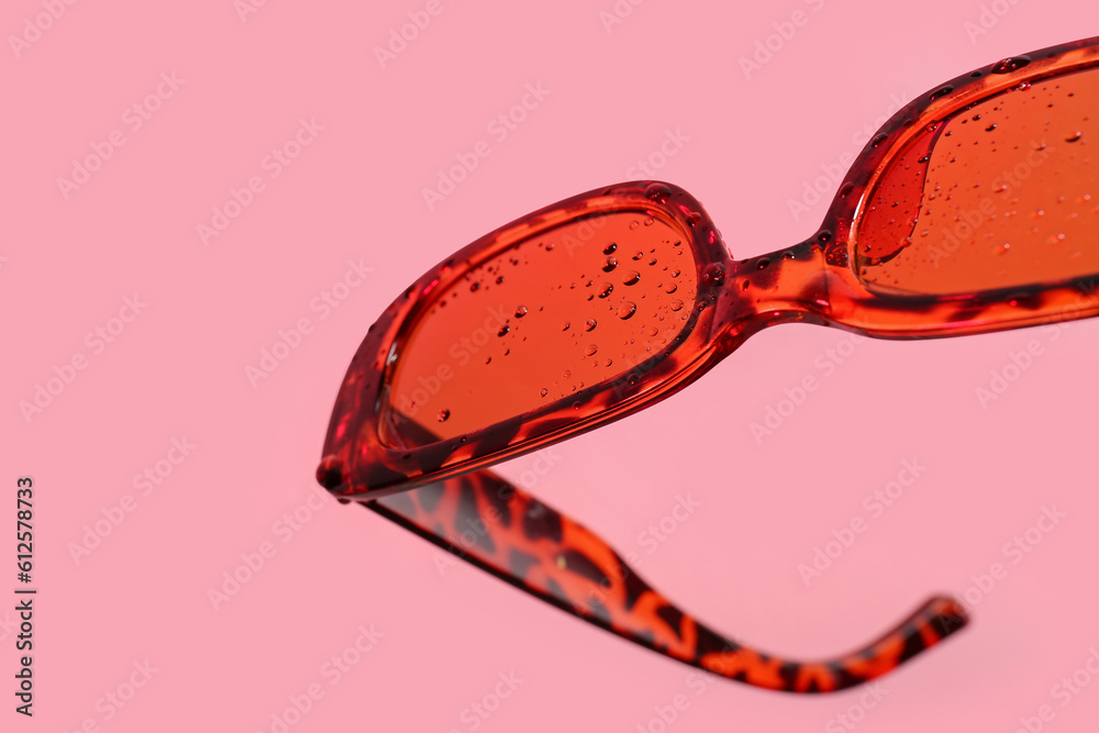 Stylish sunglasses on pink background, closeup