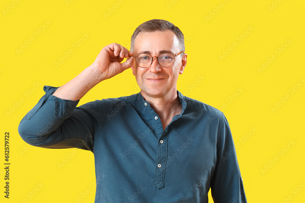 Mature man in eyeglasses on yellow background