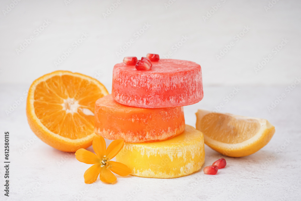 Different handmade solid shampoo, citruses and flower on light background, closeup