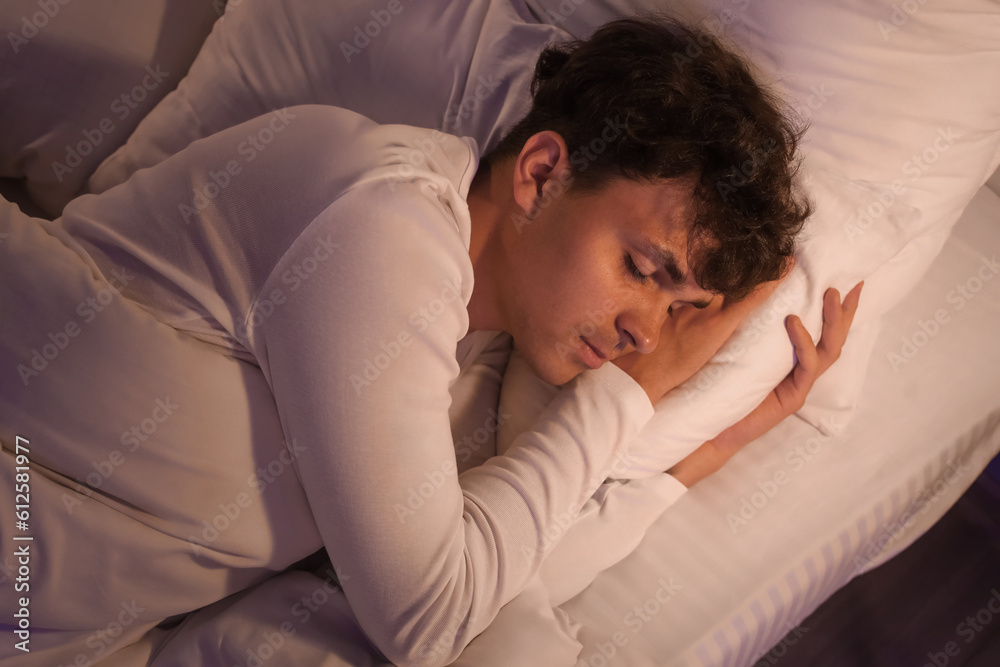 Young man sleeping in bed at night, closeup