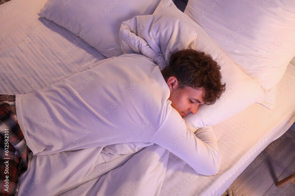 Young man sleeping in bed at night