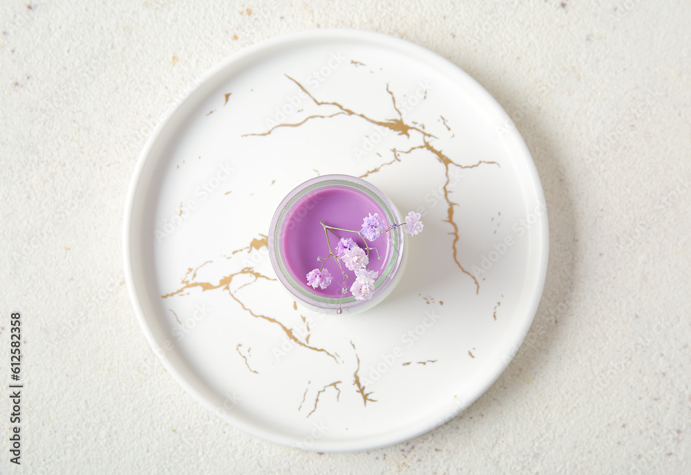 Glass of panna cotta with beautiful gypsophila flowers on white table