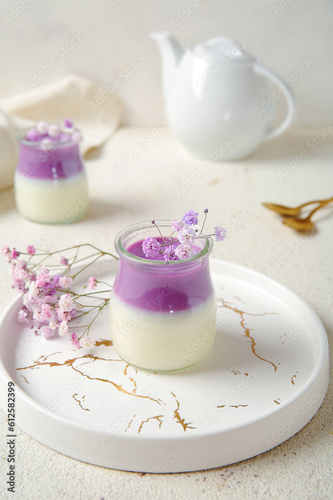 Glasses of panna cotta with beautiful gypsophila flowers and teapot on white table