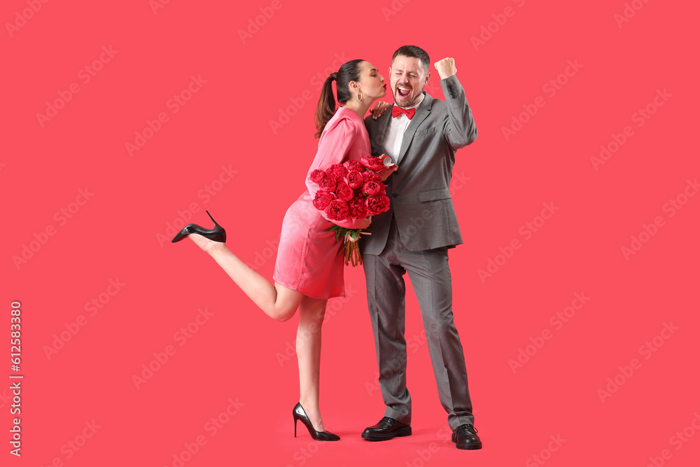 Young man proposing to his girlfriend with flowers on red background