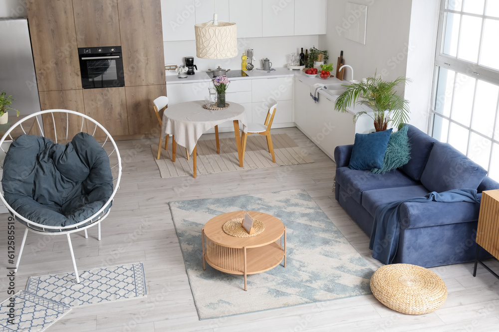 Interior of modern open plan kitchen with stylish sofa, armchair and coffee table