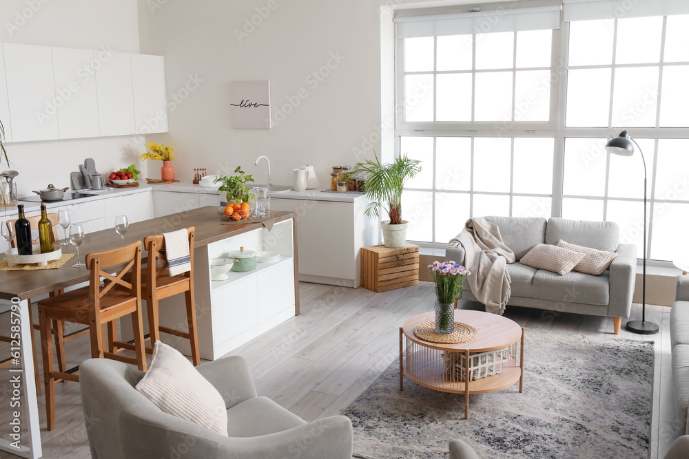 Interior of light open plan kitchen with coffee table and grey sofa