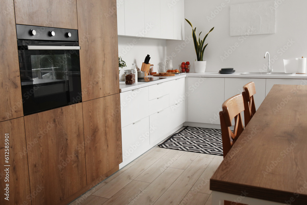 Interior of light kitchen with white counters, island and integrated oven