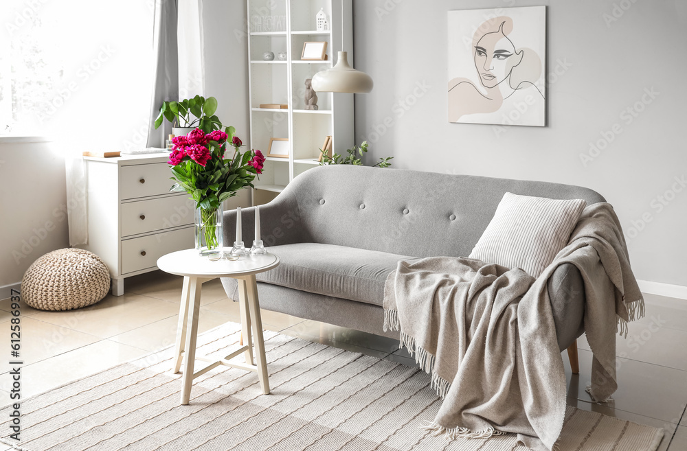 Vase with red peonies and candles on coffee table in living room