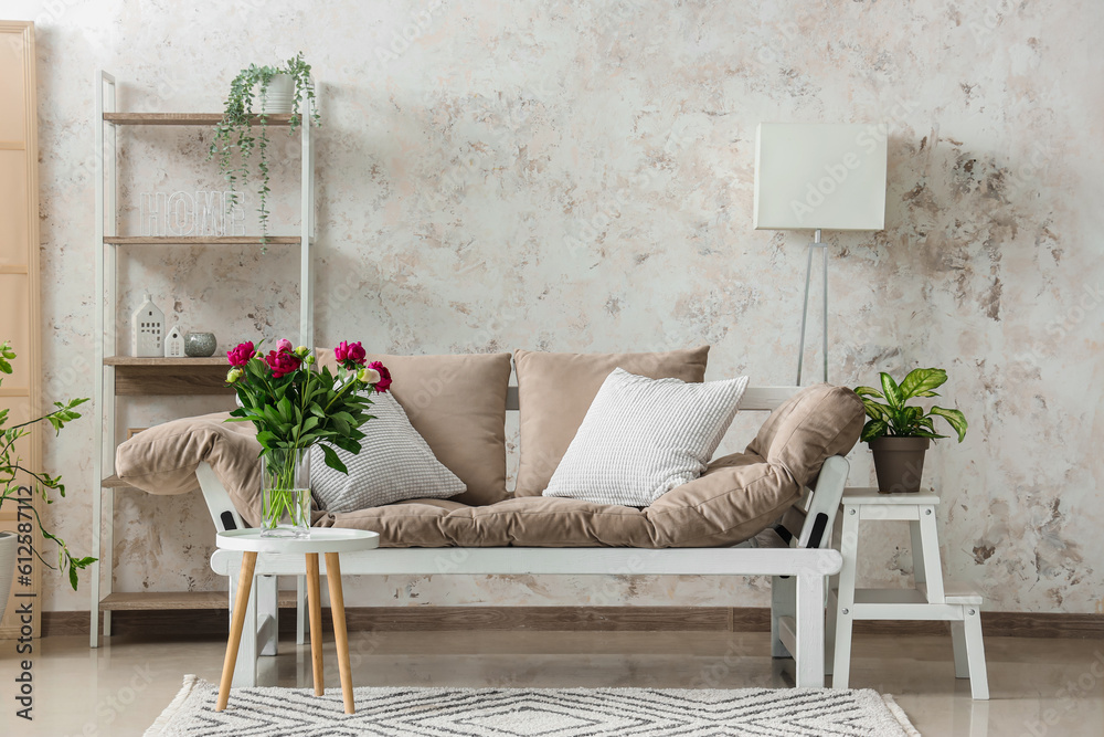 Vase with red peonies, couch and shelving unit in living room