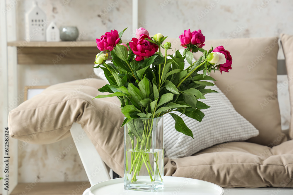 Vase with red peonies, couch and shelving unit in living room