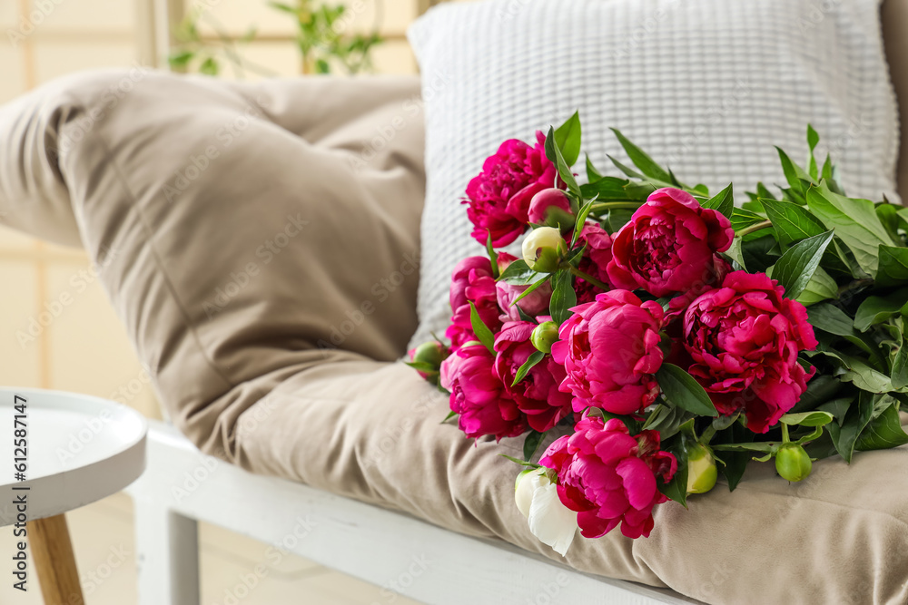 Bouquet of peonies lying on couch in living room